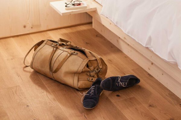 eine Reisetasche und Schuhe liegen am Boden vor dem Bett